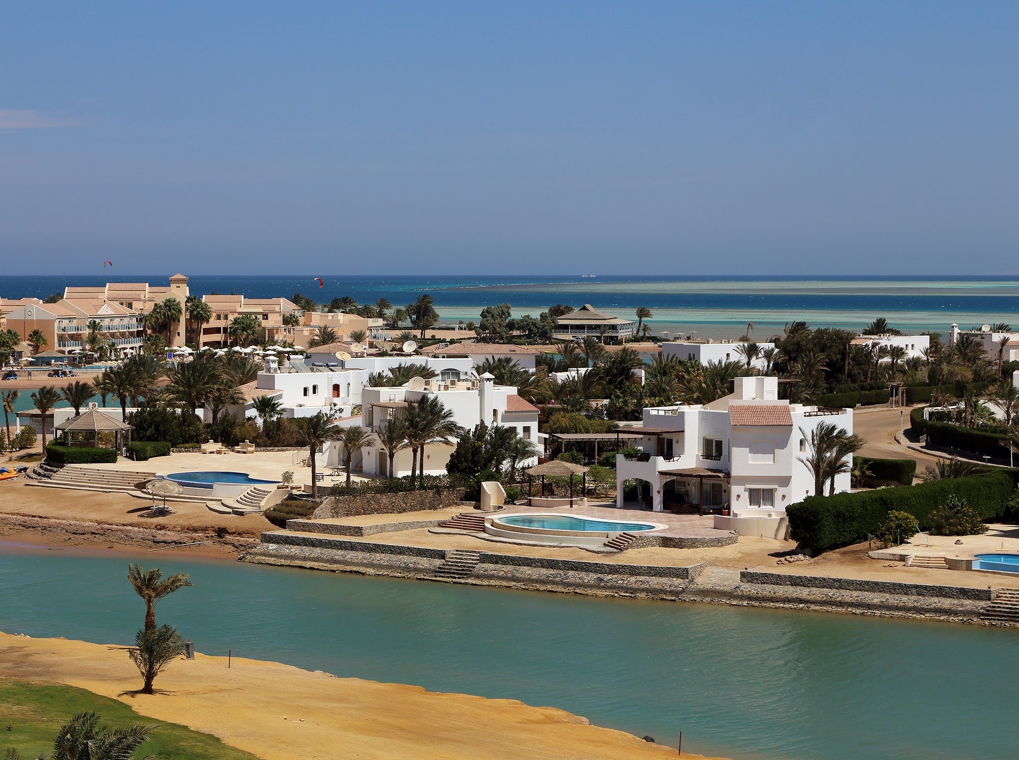 Weiße Villen mit Pools an einer Lagune in El Gouna, dahinter Riff und Rotes Meer